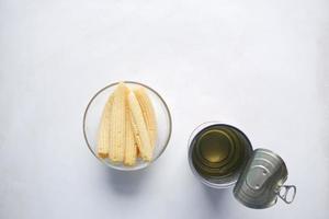 maíz para bebés en un bol con un recipiente de lata vacío sobre fondo amarillo foto