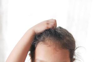child Scratching Head Against white background . photo
