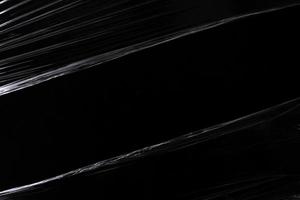 a black transparent plastic texture with hole for poster and cover art. realistic plastic wrap for overlay, copy space and photo effect. wrinkled plastic surface on black background