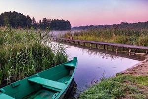 old wooden boat in the reed bushes on the bank of wide river or lake photo