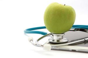 Stethoscope and green apple isolated on Tablet photo