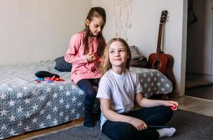 Two girls schoolgirl friends play at home, do their hairstyle photo