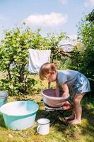 Little preschool girl helps with laundry. Child washes clothes in garden photo