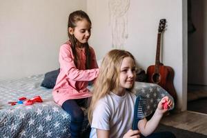 Two girls schoolgirl friends play at home, do their hairstyle photo