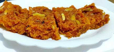 Homemade carrot halwa, traditional indian sweet, on white plate photo