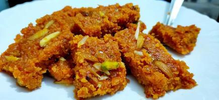 Homemade carrot halwa, traditional indian sweet, on white plate photo