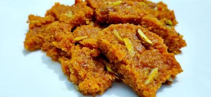 Homemade carrot halwa, traditional indian sweet, on white plate photo