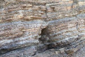 Layered rock on high steep sea bank photo