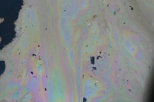 petróleo crudo en agua de mar y reflejo del arco iris foto