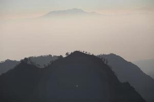 Foggy and volcano mountain during sunrise taken from Pinajagun II view point ,Indonesia photo