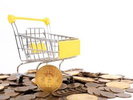 Pay crypto currency  the supermarket cart is filled with gold coins of bitcoin on a white background. Copy space photo