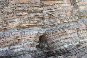 Layered rock on high steep sea bank photo