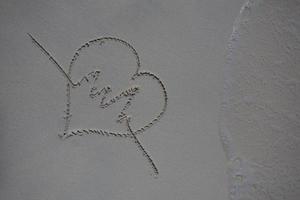 corazones dibujados en la arena de una playa foto