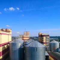 silo agrícola. almacenamiento y secado de granos, trigo, maíz, soja, contra el cielo azul con nubes. foto