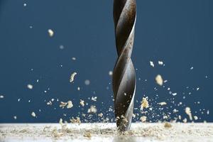 Wood drill bit in the blur with shaving on a gray background. Photo with copy space.