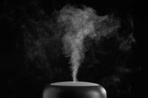 Modern air humidifier on black background. White steam close-up. The concept of humidification of the air. Photo with copy space.