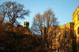 Ancient European medieval architectural building castle in golden autumn light with the blue sky background during autumn photo