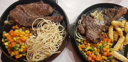 la mejor comida del mundo bistec de ternera junto con patatas fritas con deliciosa salsa de champiñones y ensalada en un hermoso plato de rayas negras foto