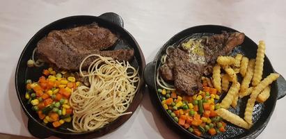 la mejor comida del mundo bistec de ternera junto con patatas fritas con deliciosa salsa de champiñones y ensalada en un hermoso plato de rayas negras foto