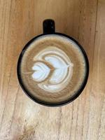 beautiful cup of cappuccino coffee with latte art in the wooden space background photo