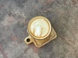 beautiful cup of cappuccino coffee with latte art in the wooden space background photo
