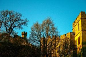 Ancient European medieval architectural building castle in golden autumn light with the blue sky background during autumn photo