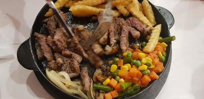 The best food in the world beef steak along with fried potatoes with delicious mushroom sauce and salad plated in beautiful black stripes plate photo