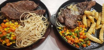 la mejor comida del mundo bistec de ternera junto con patatas fritas con deliciosa salsa de champiñones y ensalada en un hermoso plato de rayas negras foto