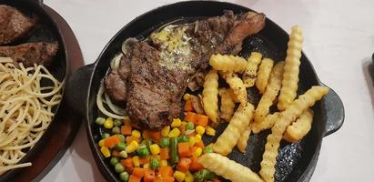 la mejor comida del mundo bistec de ternera junto con patatas fritas con deliciosa salsa de champiñones y ensalada en un hermoso plato de rayas negras foto