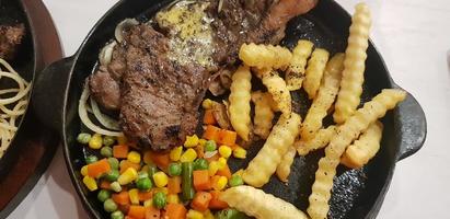 The best food in the world beef steak along with fried potatoes with delicious mushroom sauce and salad plated in beautiful black stripes plate photo