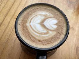 beautiful cup of cappuccino coffee with latte art in the wooden space background photo