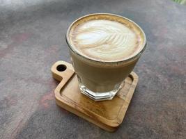 beautiful cup of cappuccino coffee with latte art in the wooden space background photo