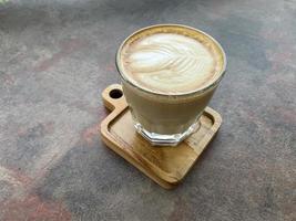 beautiful cup of cappuccino coffee with latte art in the wooden space background photo