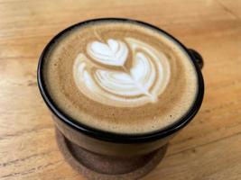 beautiful cup of cappuccino coffee with latte art in the wooden space background photo