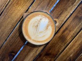 beautiful cup of cappuccino coffee with latte art in the wooden space background photo