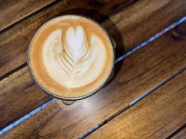 hermosa taza de café capuchino con arte latte en el fondo del espacio de madera foto