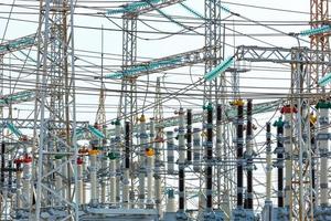 A web of electrical wires and high-voltage dielectric insulators on the metal masts of a substation during daylight hours. photo