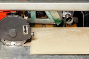 Industrial old electric tile cutter with a diamond cutting disc in front of a porcelain stoneware slab. photo