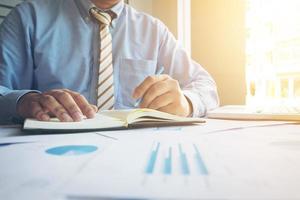 Closeup shot of business man's hands making notes on paper with many document graph and laptop. photo