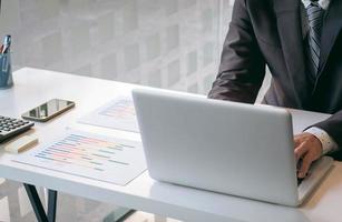 Young man working with laptop on his desk in office, man's hands on notebook computer, business person at workplace. photo