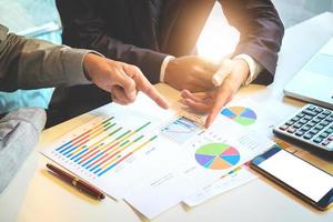 equipo de negocios dos colegas discutiendo los datos del gráfico financiero del nuevo plan en la mesa de la oficina con una computadora portátil y una tableta digital. foto