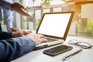 business documents on office table with smart phone and digital laptop and graph financial diagram and businessman working in the background. photo