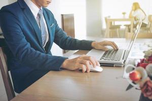 Male hands using laptop in modern coffee shop or loft, professional businessman in blue suit working on new business project with notebook computer while sitting at his office. photo