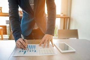 business man working with tablet and diagram graph data on wood table in office, business concept. photo