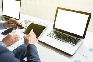 business documents on office table with smart phone and digital laptop and graph financial diagram and businessman working in the background. photo