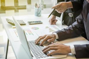 el equipo de empresarios que trabaja en el escritorio de la oficina y usa una tableta de pantalla táctil digital da detalles, computadora y objetos en la mesa a la luz de la mañana. foto