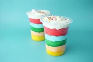 rainbow color cake in a plastic container on table photo