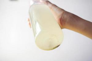 sosteniendo un vaso de agua sucia contra el fondo blanco foto