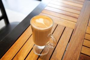 a cup of late coffee with flower shape design on top at cafe photo