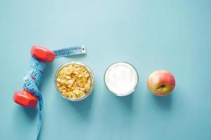 top view of cereal, apple and dumbbell on blue background photo